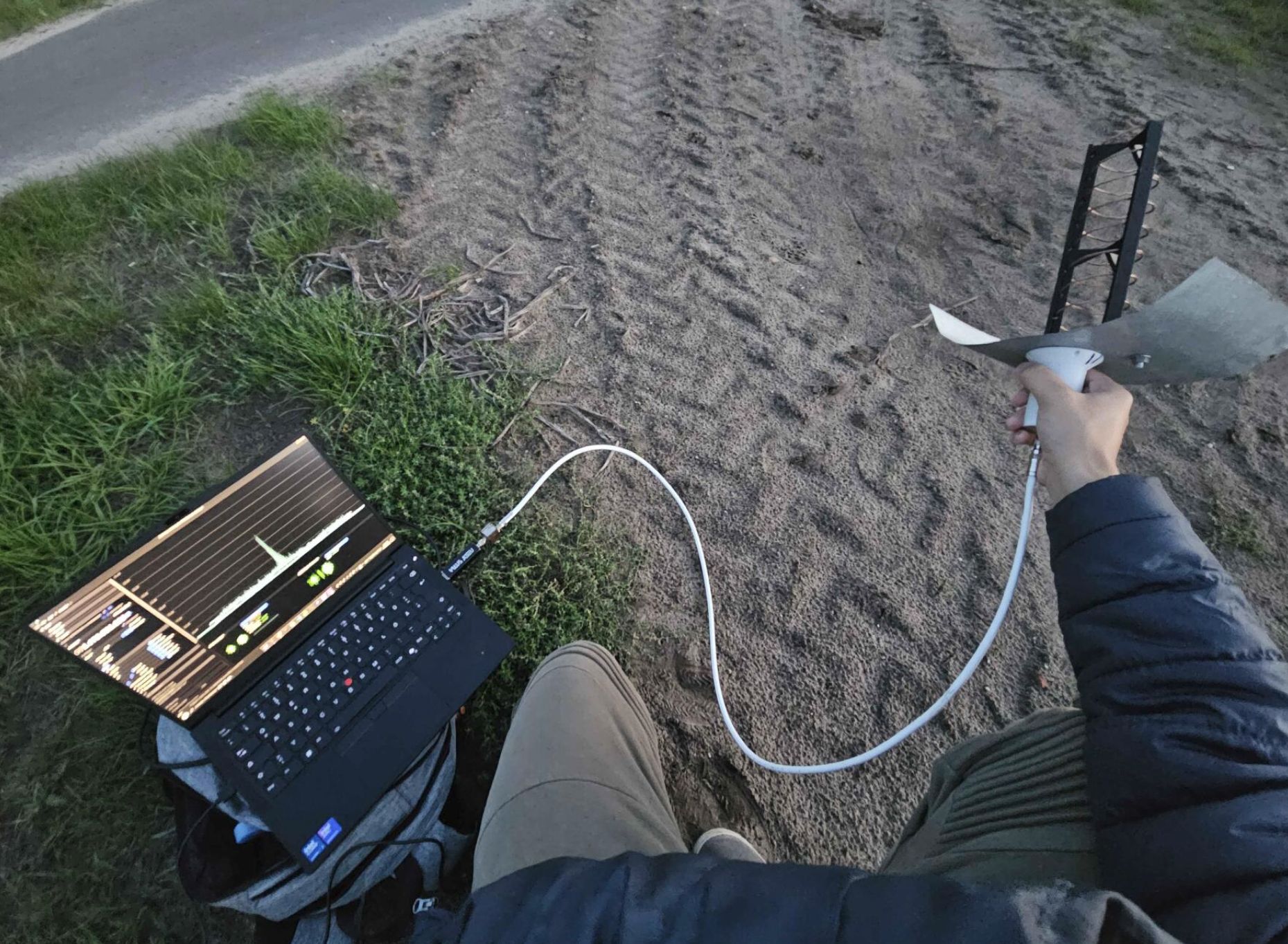 A picture of me holding the helix on the roadside, the laptop showing SatDump decoding Elektro-L2 GGAK.