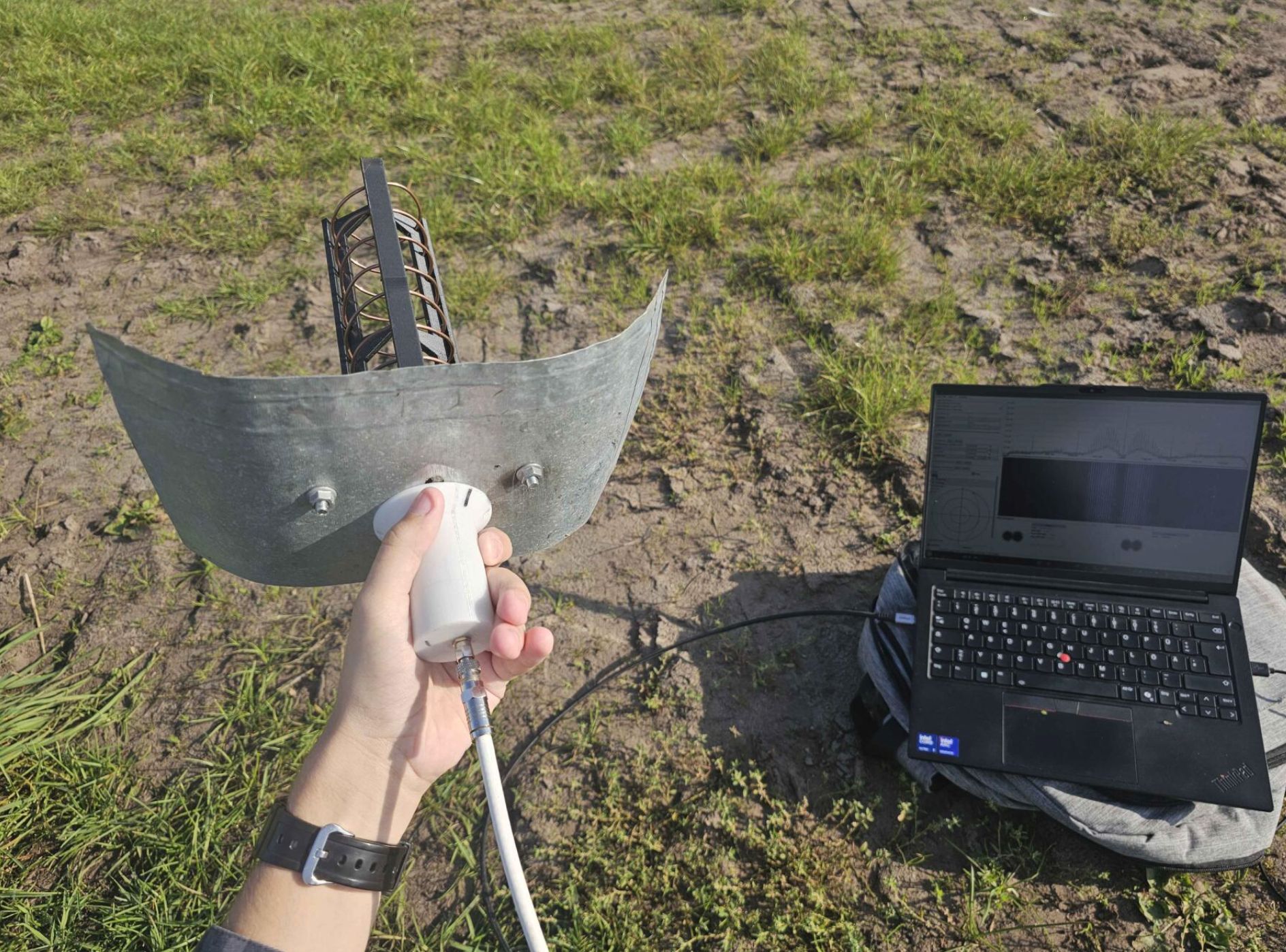 A picture of me holding the helix, with my laptop showing SatDump decoding Meteor HRPT